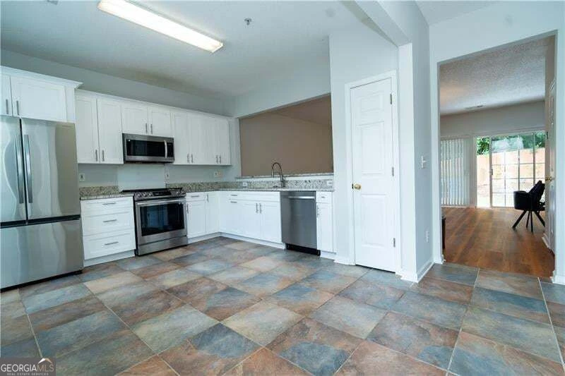 Updated kitchen with white cabinetry and stainless steel appliances